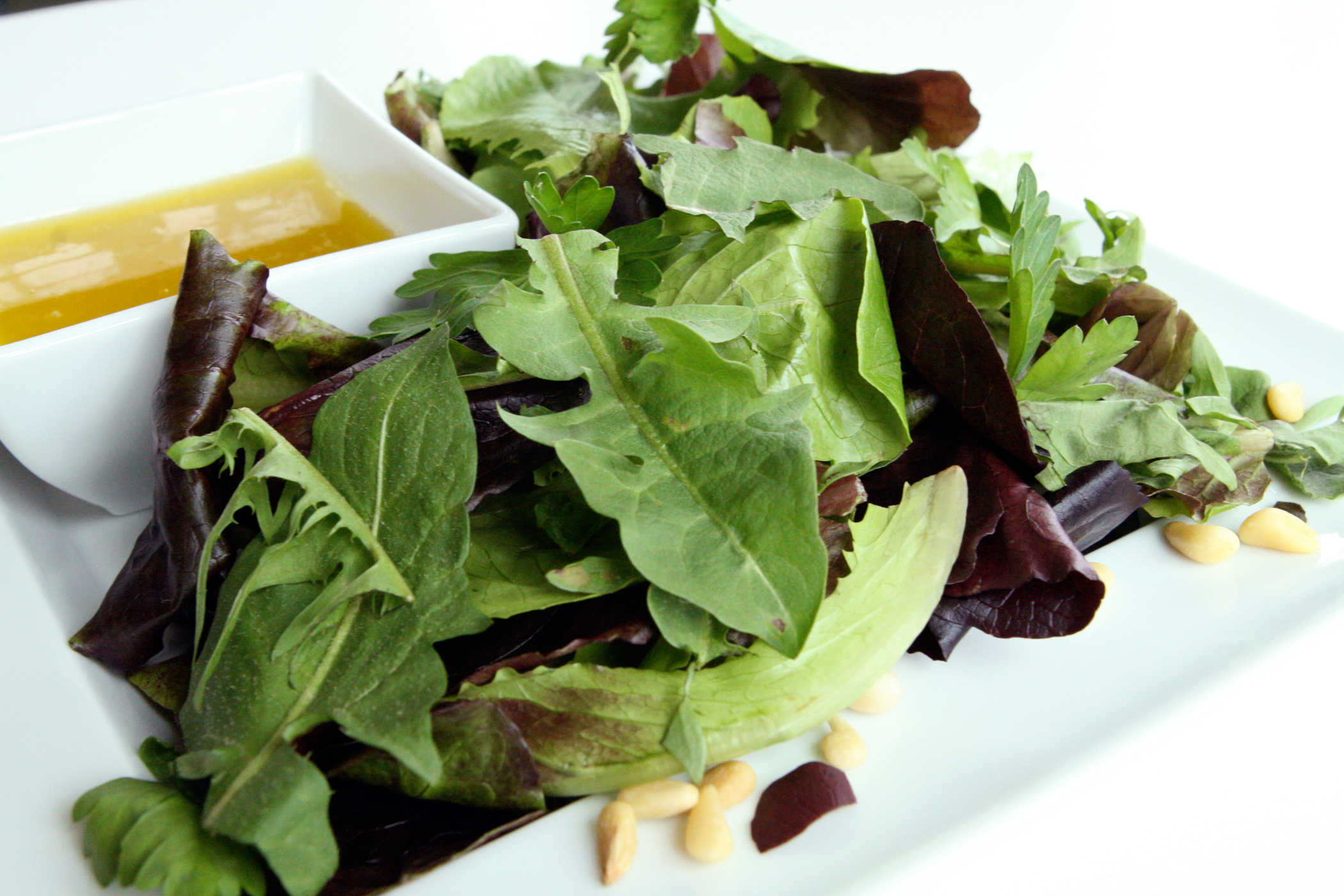 Close-up of a salad dish with nuts and olive oil in a small dip dish