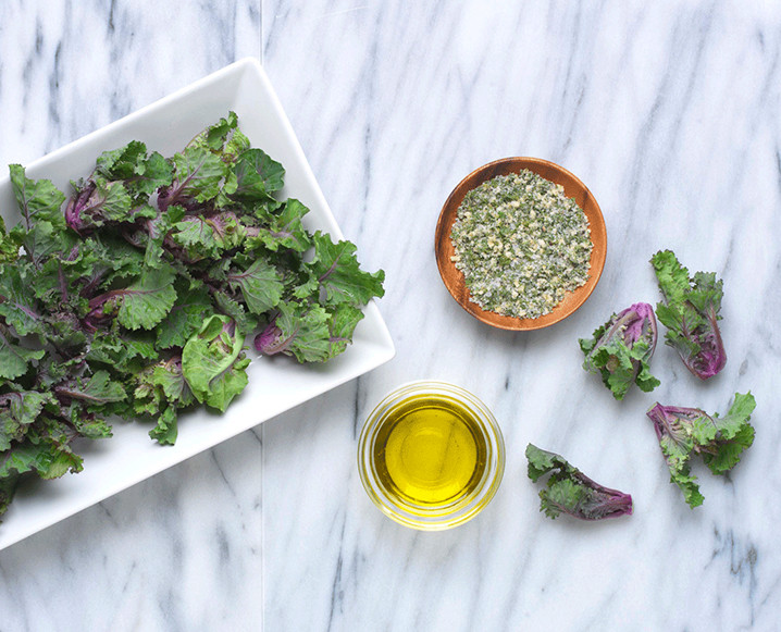 Aerial shot of a marble surface with a plate of salad, a small bowl of spices and glass of oil