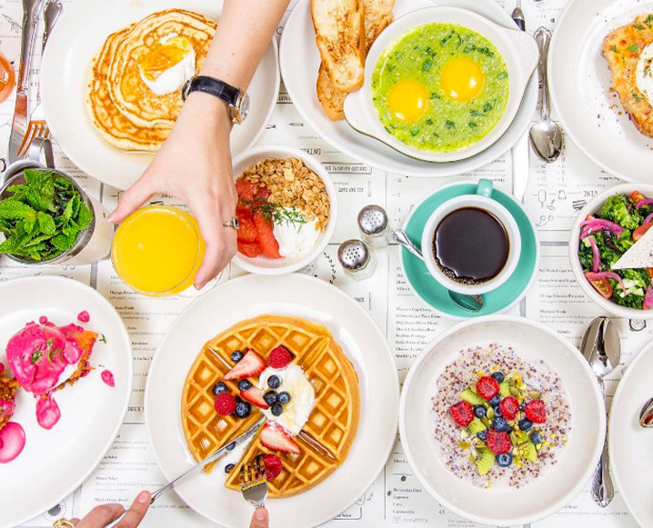 Aerial view of a brunch spread at Jack's Wife Freda restaurant showing eggs, waffles, pancakes and more