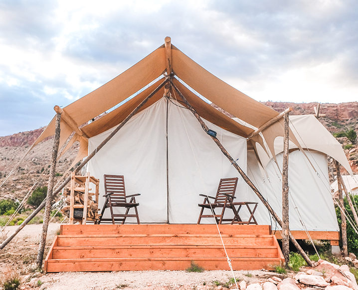 Medium shot of an assembled tent with wooden stairs and a porch with two wooden chairs on it