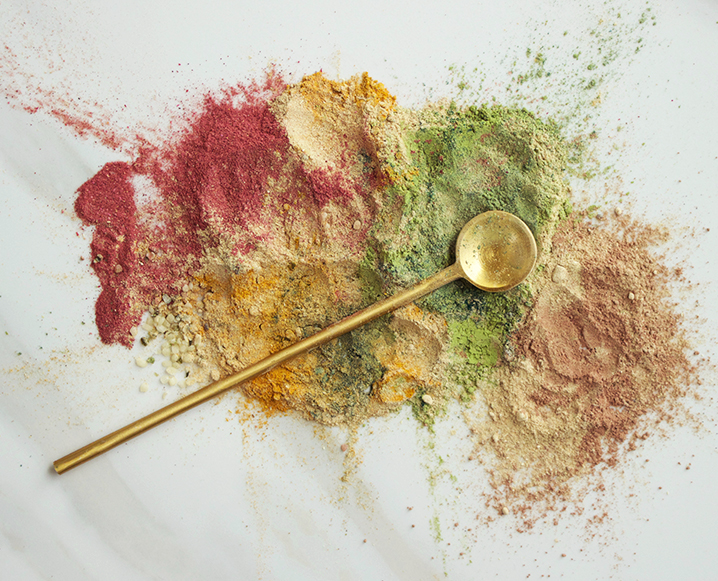 Aerial shot of different colorful powders with a brass long handle spice spoon